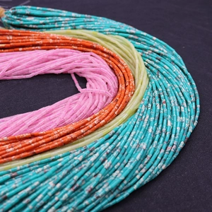 Gros plan de perles tubes en pierre 2x4mm turquoise, rouge et jaune pour création de bijoux