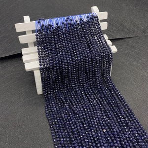 Gefacetteerde blauwe zandsteen kralen voor sieraden getoond op een miniatuur witte bank