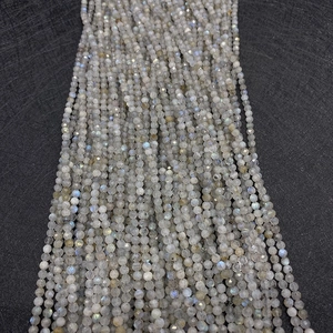 Macro detail of faceted labradorite beads with shimmering blue flashes on black texture