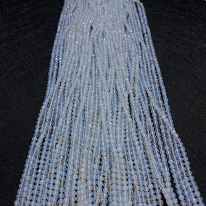 Gros plan de perles d'opale facettées bleu clair sur tissu noir pour bijoux DIY