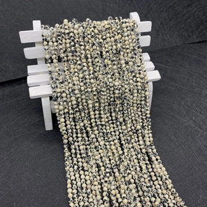 Macro detail of natural faceted Dalmatian Jasper stone beads strand on white bench