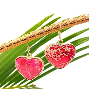 Heart-shaped natural stone drop earrings with gold edges hanging on a natural wood branch