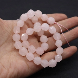 Detailed macro view of faceted rose quartz beads being held to show natural pink stone texture