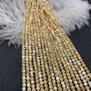 Detailed view of faceted round yellow shell beads with iridescent luster for DIY jewelry