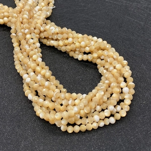 Macro detail of faceted champagne mother of pearl beads with iridescent natural shell luster