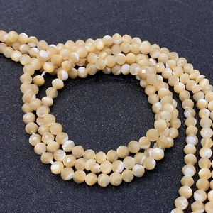 Detailed view of faceted natural shell beads for DIY jewelry making in warm yellow tones