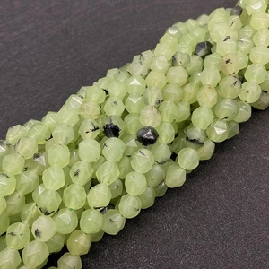 Macro detail of faceted green prehnite beads with natural black needle inclusions for DIY
