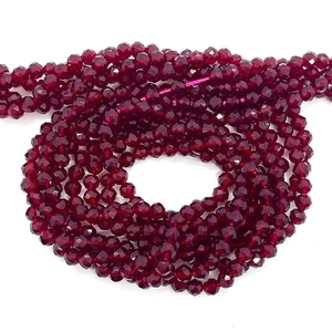 Macro view of faceted deep red spinel glass beads in a spiral strand for DIY jewelry