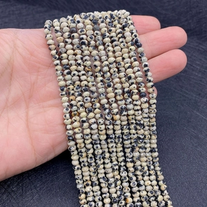 Detailansicht facettierter cremefarbener Natursteinperlen mit schwarzen Punkten für DIY