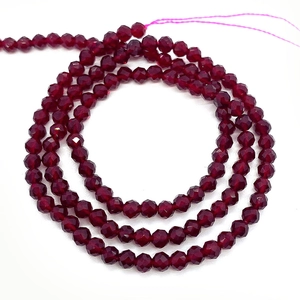 Faceted 2mm dark purple spinel glass beads arranged in concentric circles on white background