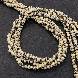 Makroaufnahme von 2-3mm facettierten Dalmatiner-Jaspis-Perlen für DIY-Schmuck