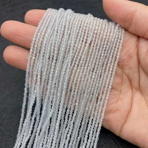 Faceted white cat eye beads for jewelry making shown in hand for size contrast