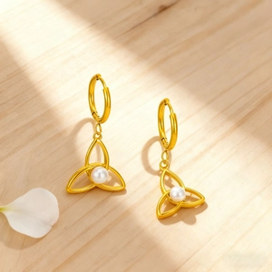 Golden Celtic knot hoop earrings with white pearls on a natural wood background