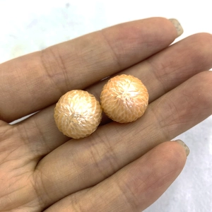 Macro shot of two carved orange freshwater pearls showing detailed dragon scale texture
