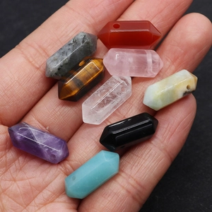 Detailed macro view of various natural hexagonal crystal stone pendants with drill holes
