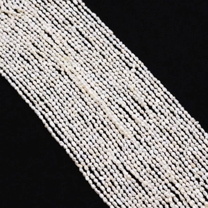 Macro shot of high-luster white freshwater seed pearls on a contrasting black background