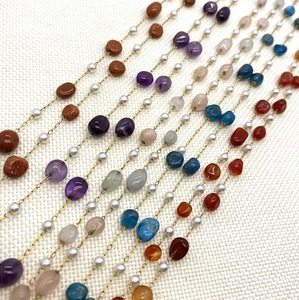 Detail view of multi-color natural gemstones and ABS imitation pearls on gold stainless chains