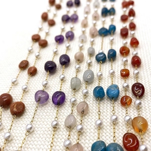 Detail of gold stainless steel chain with colorful natural stones and ABS pearls