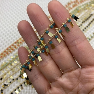 Detail einer Boho-Goldkette mit facettierten blauen Perlen und Pfeilanhängern