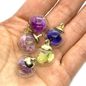 Close-up of 16x21mm clear glass ball pendants with dried flowers and gold metal caps