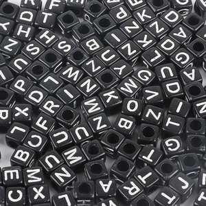 Macro view of square acrylic black beads with white uppercase letters and center holes
