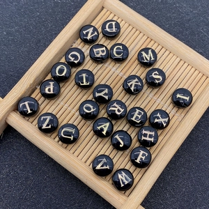 Macro shot of circular shell beads with gold-engraved letters for DIY jewelry