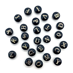 DIY shell beads with gold 26 English letters on black surface for necklaces