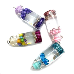 Macro detail of cylinder glass vial pendants with resin mermaid foam and shell fillers