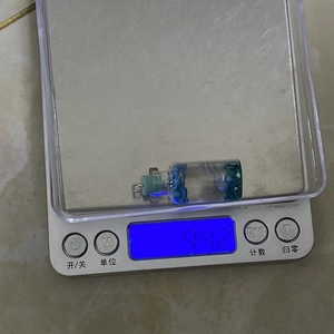 Cylindrical glass bottle pendant weighing 9.42g on a scale for product measurement