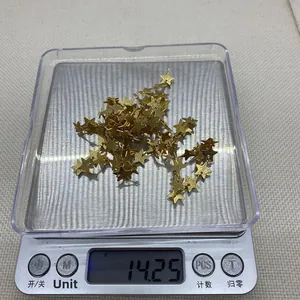 Primer plano de varios dijes de metal en forma de estrella dorada en una báscula digital