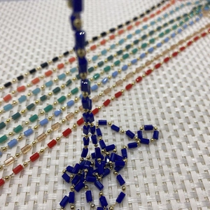 Detailed macro view of colorful cylinder stone beads on a golden copper jewelry chain