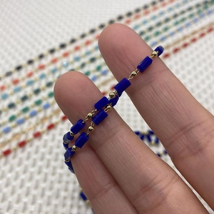 Detailed close-up of dark blue cylindrical beads and golden metal spacers for DIY jewelry