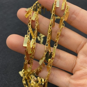 Macro shot of twisted copper chain with metallic gold rectangular pendant charms