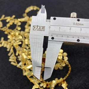 Macro shot measuring the thickness of golden twist chain link with a digital caliper