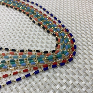 Detailed macro view of colorful cylinder stone beads on fine gold plated copper chains