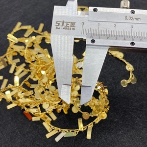 Macro detail of golden twist chain measuring round pendant size with a digital caliper
