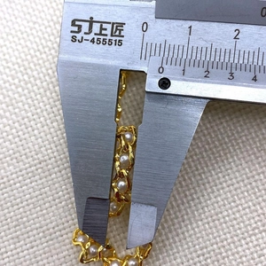 Dettaglio della catena dorata da 4mm con perle bianche misurata con un calibro a corsoio