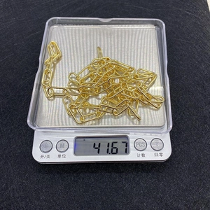 Detailed close-up of 8x13mm gold copper oval chain link being weighed on a scale