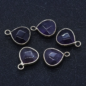 Macro view of five faceted purple stone teardrop pendants with gold metal frames for DIY