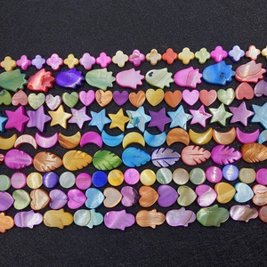 Assorted colorful shell beads in cross, star, and heart shapes on a dark background