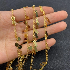 Golden twisted chain with round and rectangular charms wrapped around fingers