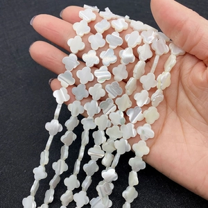 Makroaufnahme von Kleeblatt-Perlen aus weißem Perlmutt für die DIY-Schmuckherstellung