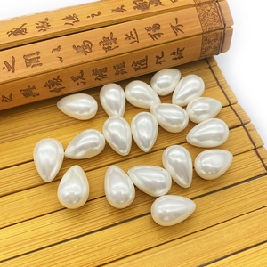 Waterdrop-shaped white imitation pearls on a vintage bamboo mat for DIY jewelry making
