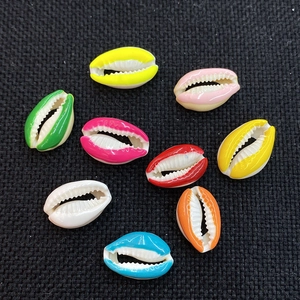 Colorful natural cowrie shell beads for DIY jewelry making on a dark textured surface