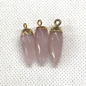 Macro-opname van gefacetteerde roze kwartshangers met gouden lussen voor DIY-sieraden