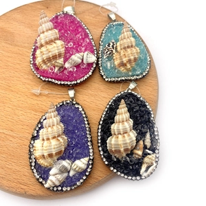 Handcrafted teardrop stone pendants with shell inlay and crystal edges on wood tray