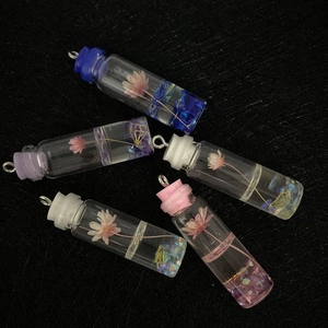 Five cylindrical glass resin pendants with dried pink flowers and colorful glitter