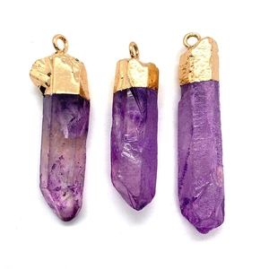 Dettaglio di tre ciondoli in cristallo viola sfaccettato con cappucci in metallo dorato