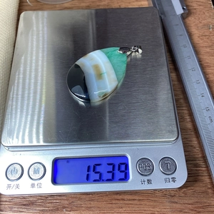 Teardrop agate stone pendant weighing 15.39 grams on a digital scale for necklace making
