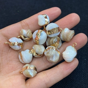 Handheld view of irregular natural shell pendants with gold trim for DIY jewelry